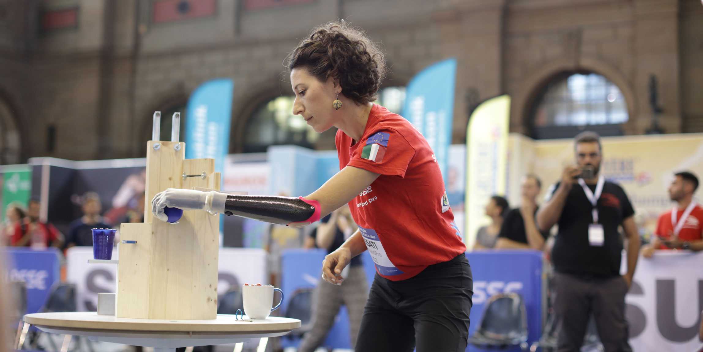 Woman with prosthetic arm grabs a blue ball
